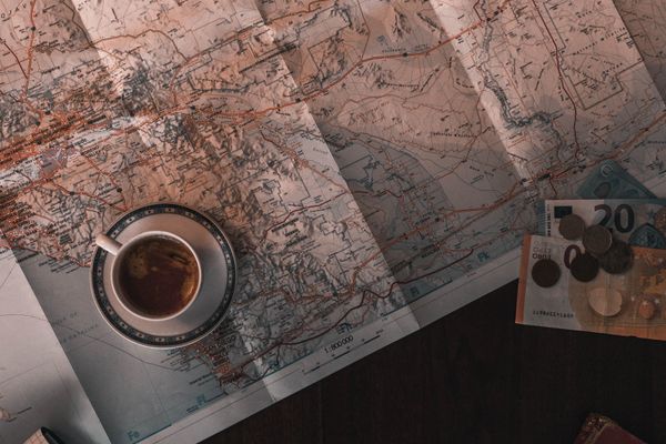 Notebook, map, and coffee on a table beside an itinerary