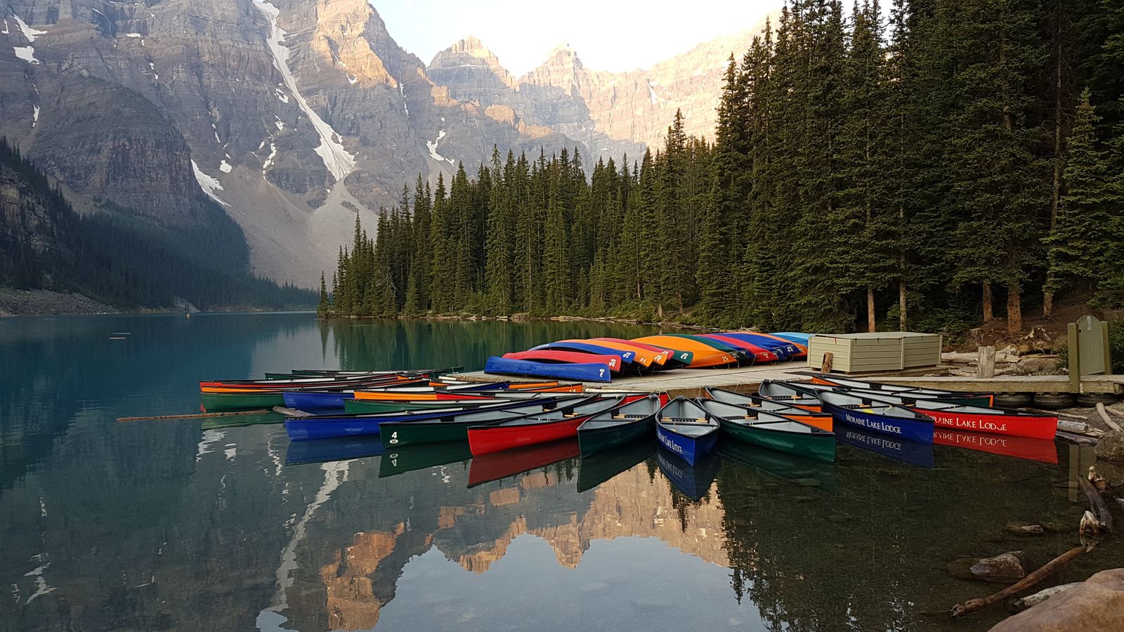 Private tours Canada: a mountain lake at dusk with a canoe at the shore